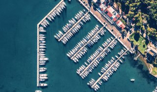 Crowded marina and blue sea with boats coming in and out on a sunny day